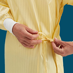 A health-care employee wears a yellow isolation gown.